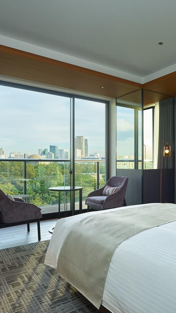 広々とした窓から街並みが見える、モダンで上質なホテルの客室。会員限定クーポンの利用で実現できる贅沢な滞在をイメージ。