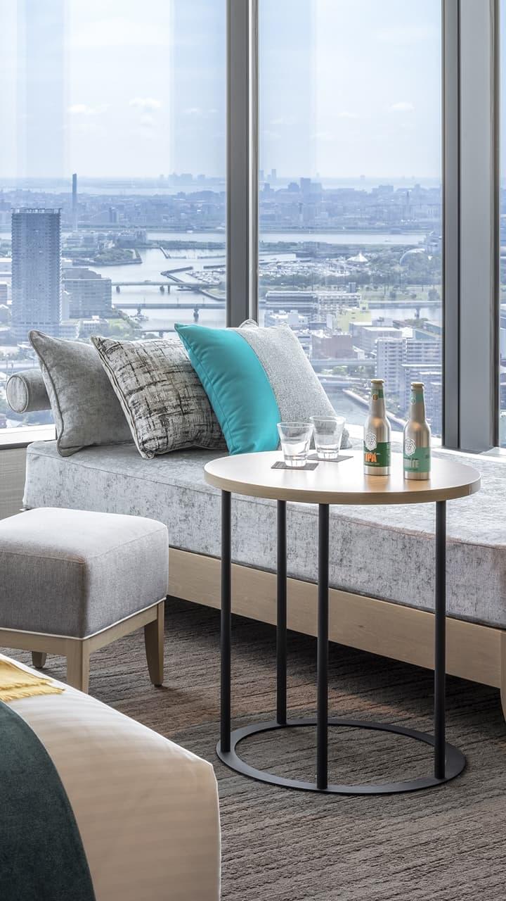 広々とした窓から街並みが見える、モダンで上質なホテルの客室。貯めたポイントで交換できる贅沢な滞在をイメージ。